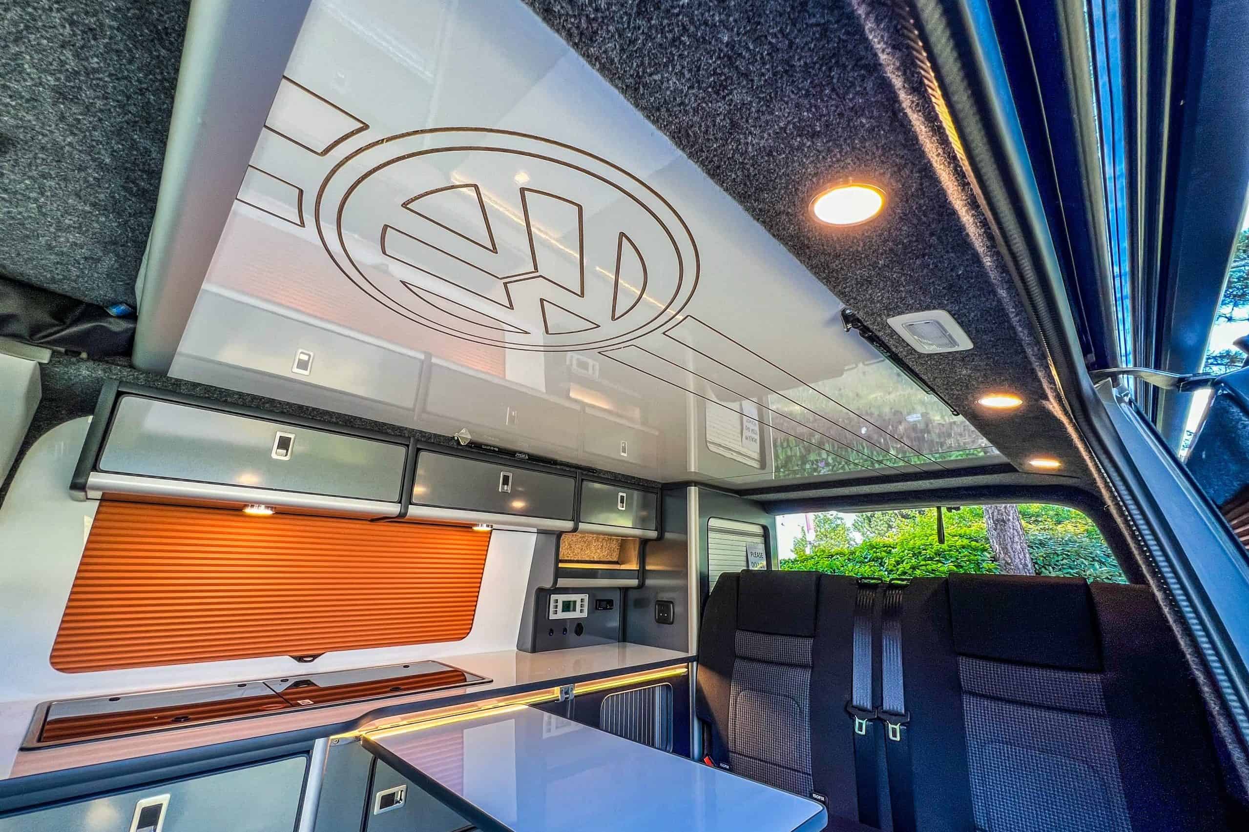 Interior of a VW vehicle conversion featuring a custom workspace and seating area.