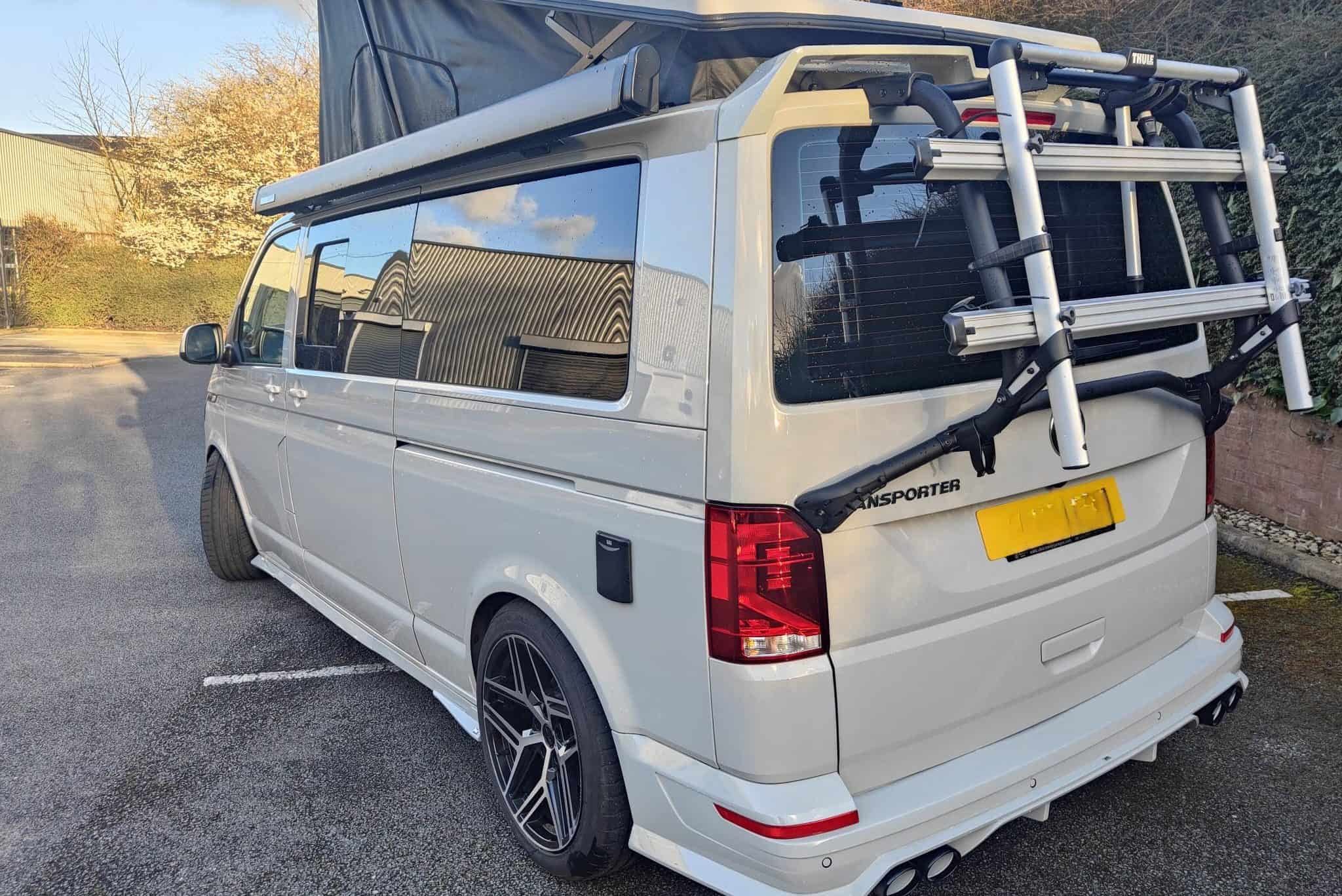Van conversion with roof rack and bike carrier for outdoor adventures.