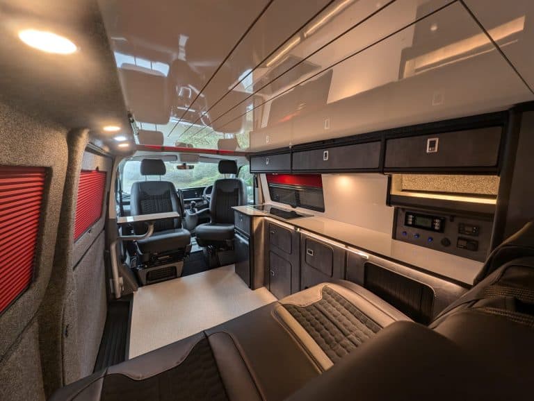 Interior van conversion with custom cabinetry and seating for travel comfort.