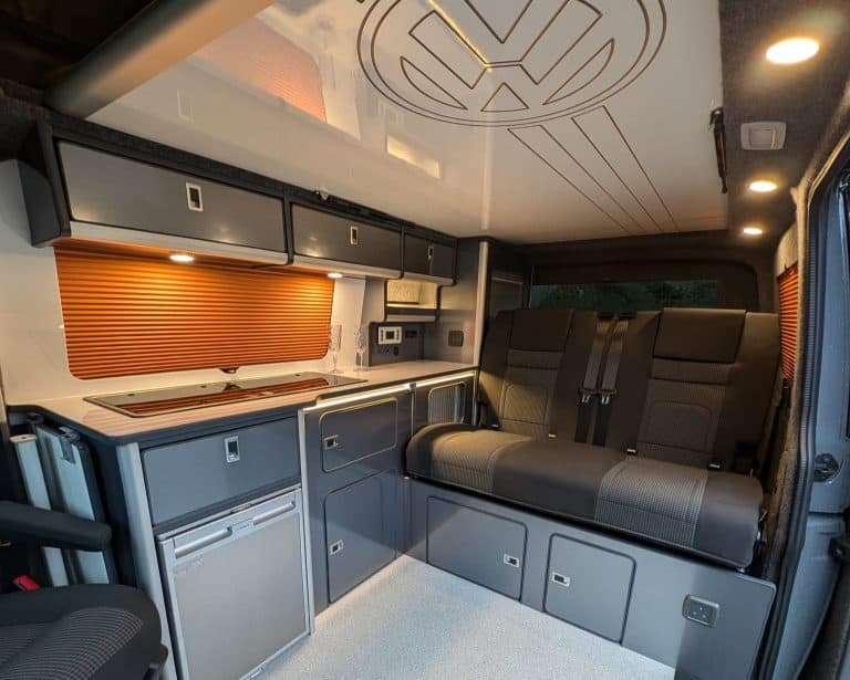 Modern camper van interior with kitchen and seating area for travel comfort.