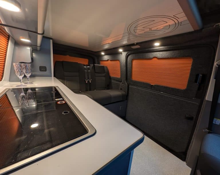 Interior of a custom camper van with comfortable seating and modern kitchen facilities.