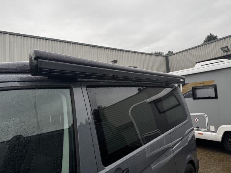 Custom camper van conversion with awning, tinted windows, and modern design.